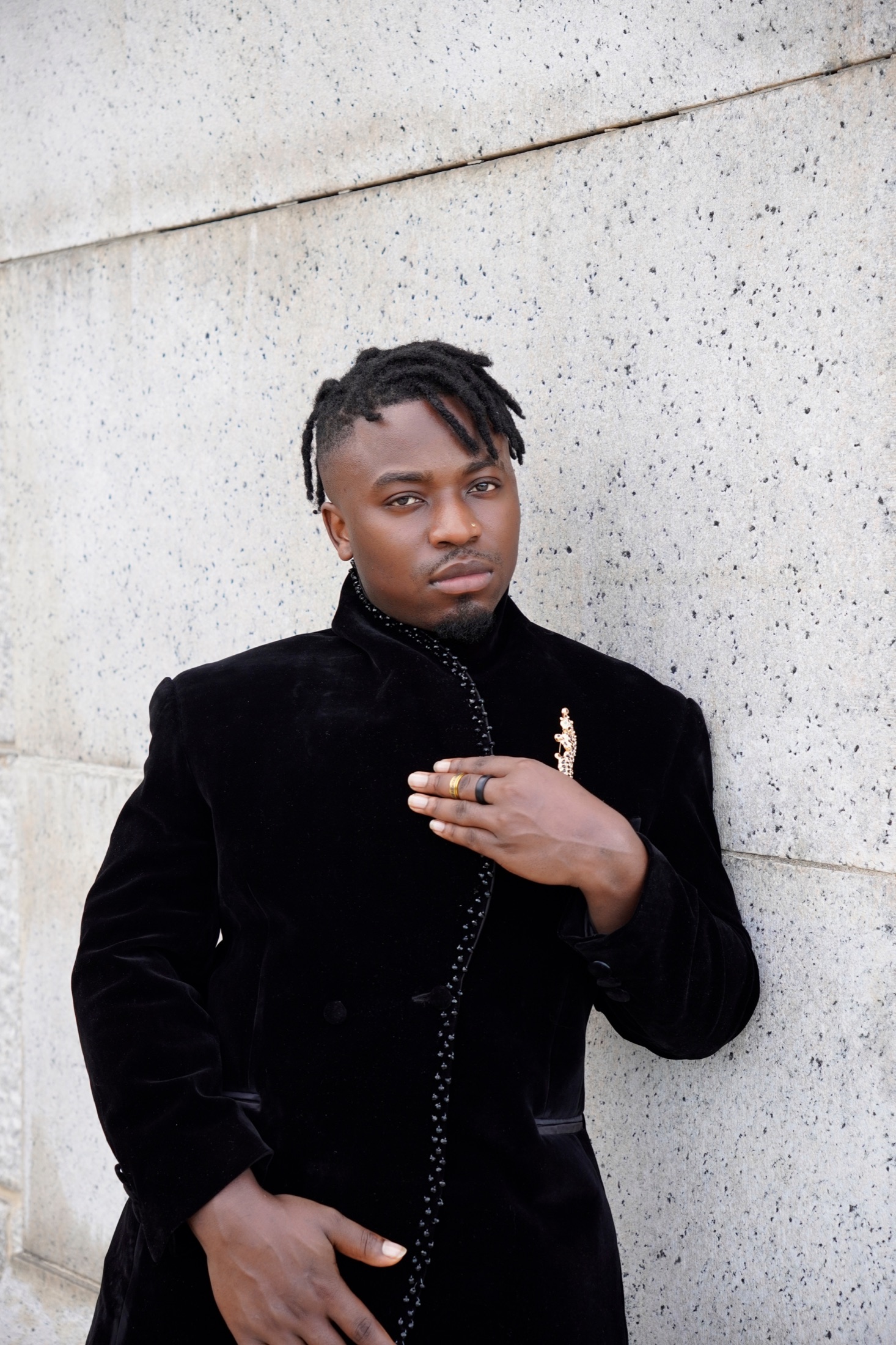 Close-up portrait in black velvet against a stone wall